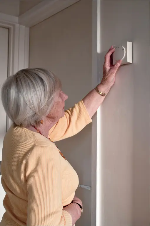 Homeowner adjusting a thermostat on the wall