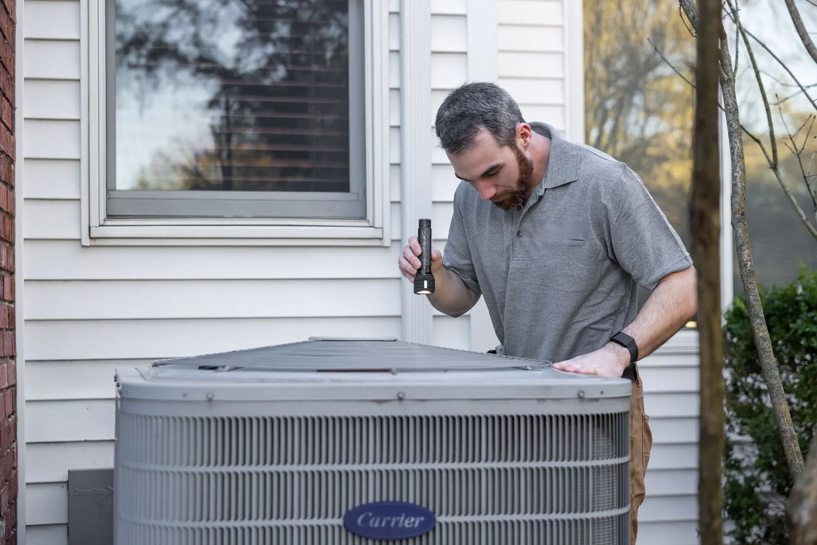 Technician setting a new AC condenser on a pad