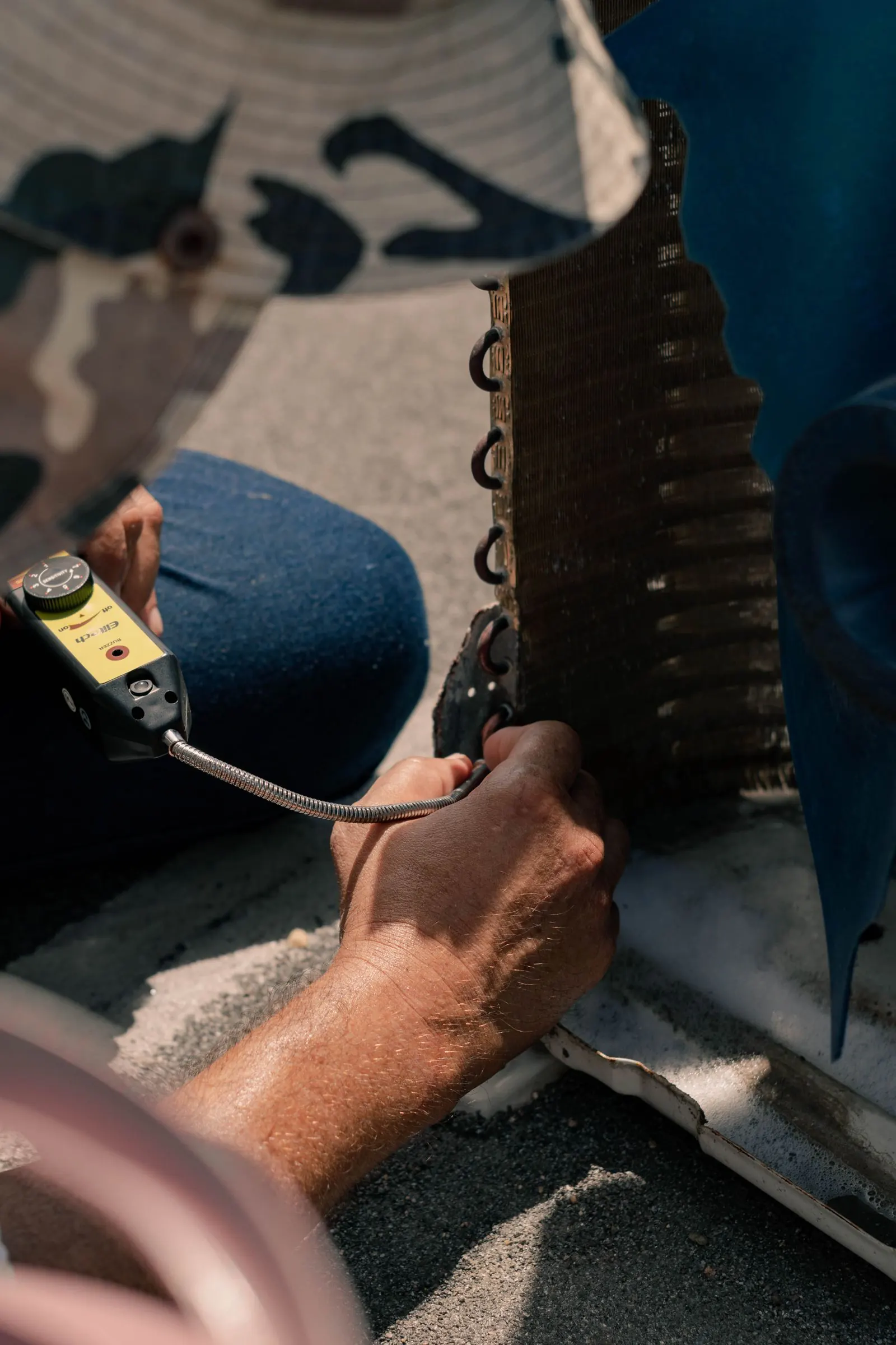 Technician using a leak detector on AC refrigerant lines