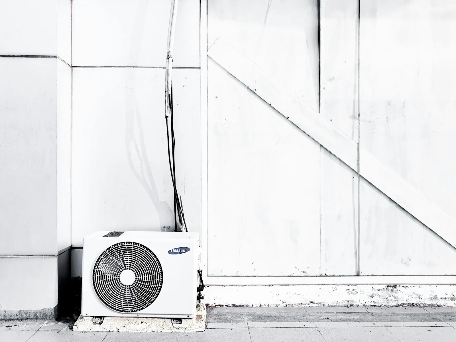 Heat pump outdoor unit beside a home with snow on the ground