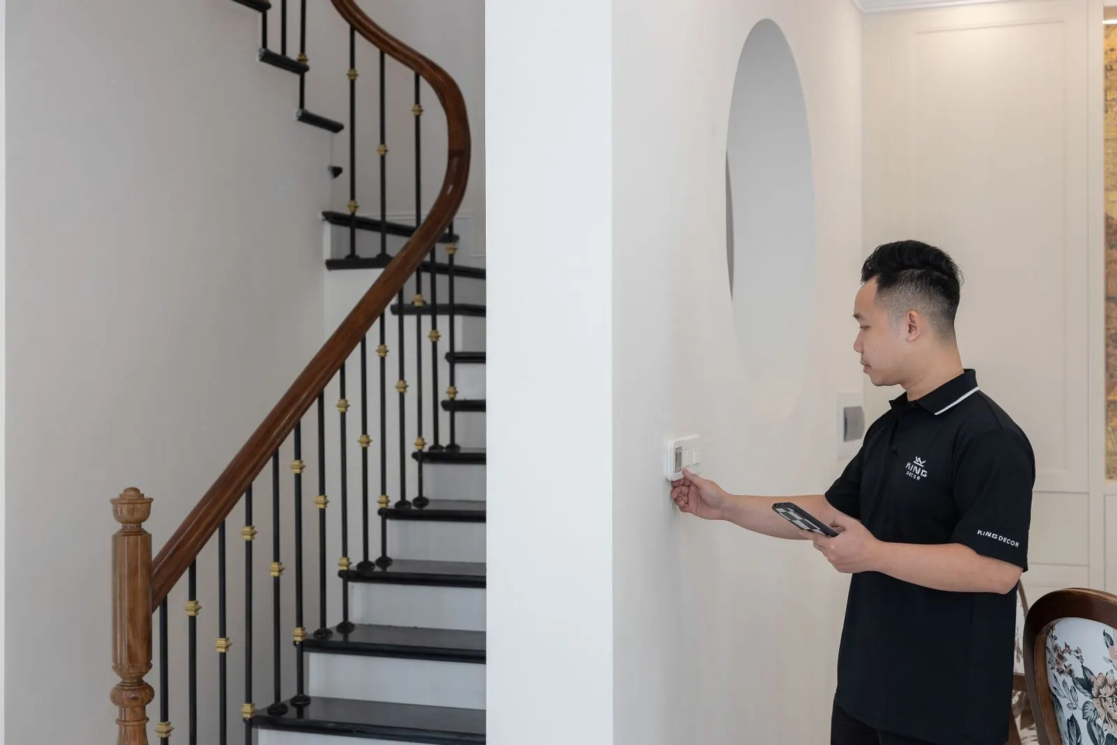 Technician mounting a new thermostat on a hallway wall